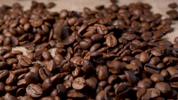 Roasted coffee beans with smoke. Slow motion of arabica coffee seeds falling. alt