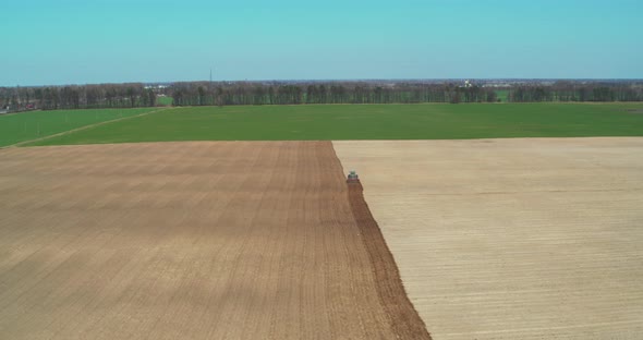 Tractor Plow Cultivating Field in Spring General Plan Aerial View alt
