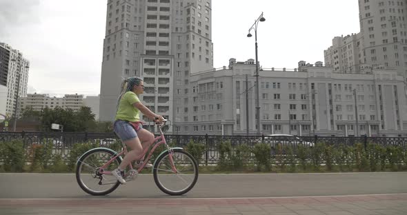 Bright Girl Rides Color Bike Around City alt