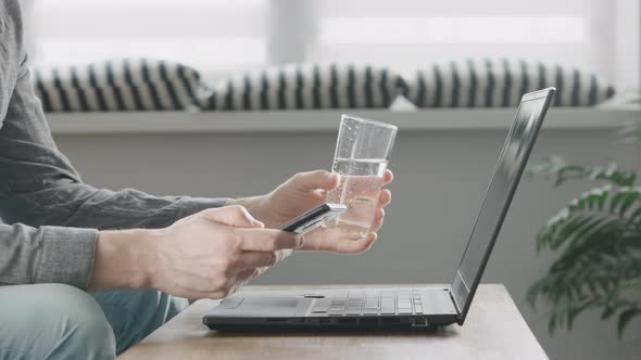 An Unrecognizable Man Uses Mobile Internet From His Smartphone to Work on a Laptop alt