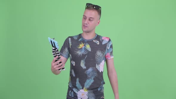 Happy Handsome Man with Sunglasses Vlogging and Showing Phone alt