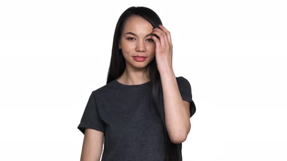 Portrait of Beautiful Asian Woman 20s in Casual Tshirt Smiling and Putting Her Long Black Hair alt