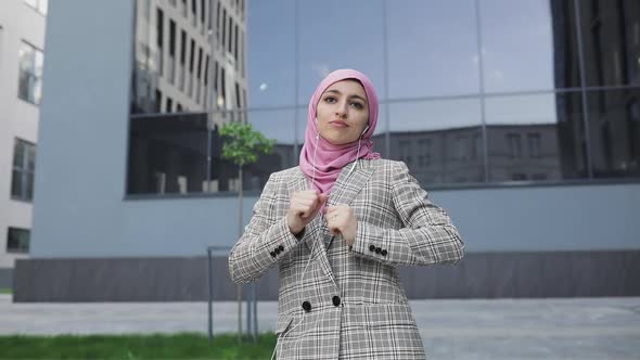 Young Woman Wearing Hijab Headscarf Listen Music on Phone By Earphones, and Dance at the Street