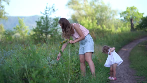Mom Puts a Wreath of Wildflowers on Her Daughter's Head in Nature