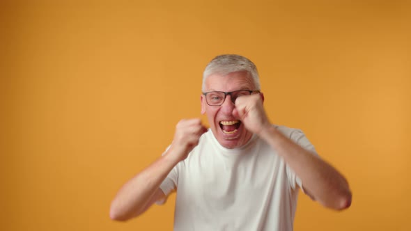 Happy Senior Man Dancing on Yellow Background