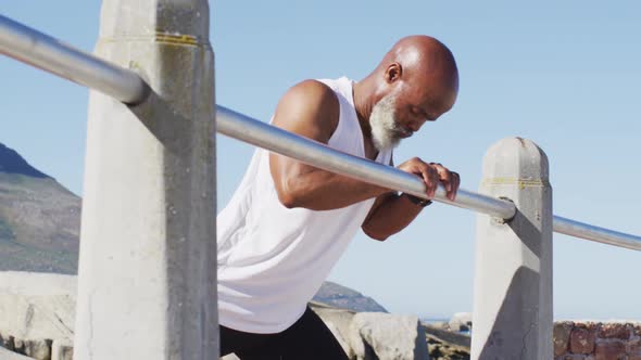 Senior african american man exercising stretching on rocks by the sea alt