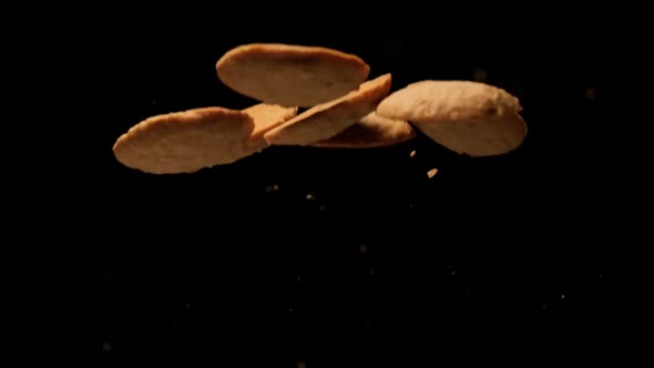 Slow motion cookies flying on black background. alt