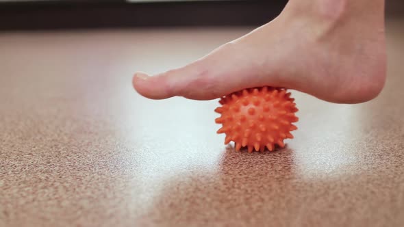 Closeup a Woman Rolls a Massage Ball with Thorns on the Floor of the Foot