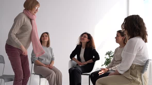 Mature Woman is Standing Up and Telling Her Story in a Psychotherapist's Office During Group Therapy alt