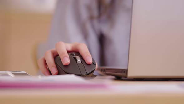 Close up of click black computer mouse on a work desk. Asian woman with curly hair working with a PC alt