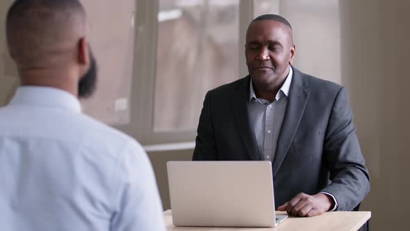 Two African Colleagues Customer and Salesperson Sitting in Office Talking Discussing Back View alt