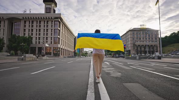 Woman Runs on Main Street of Kyiv Lifting Ukrainian Flag alt