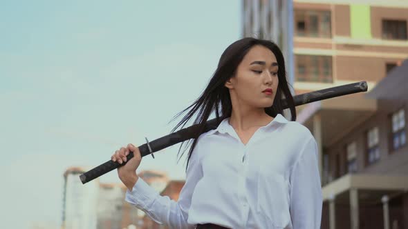 Japanese Girl Look Into Camera, Standing in Wind with Traditional Samurai Sword alt