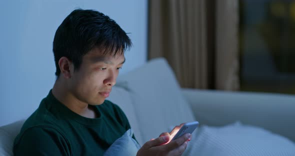 Man look at cellphone inside home alt