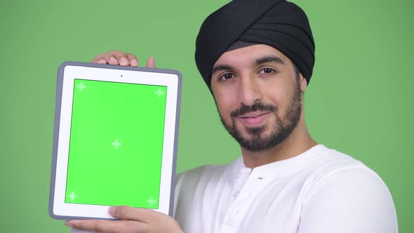 Young Happy Bearded Indian Man Showing and Looking at Digital Tablet