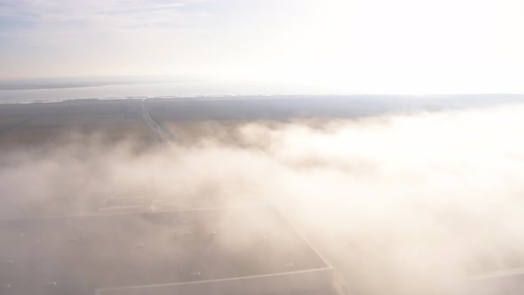 Aerial Top View Drone Flies Through Heavenly Fluffy Rain Clouds Rolling Over Green Forest and Field alt