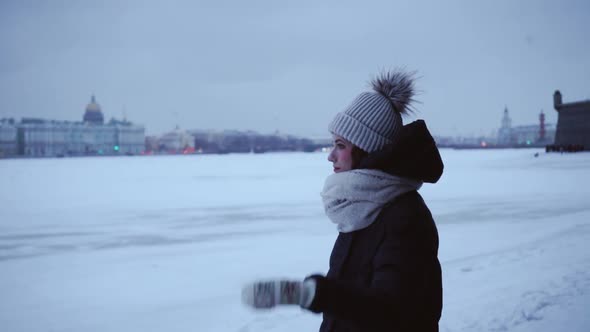 Young Girl in a Warm Jacket and Hat in the Cold. Young Woman on a Background of Snowdrifts and a