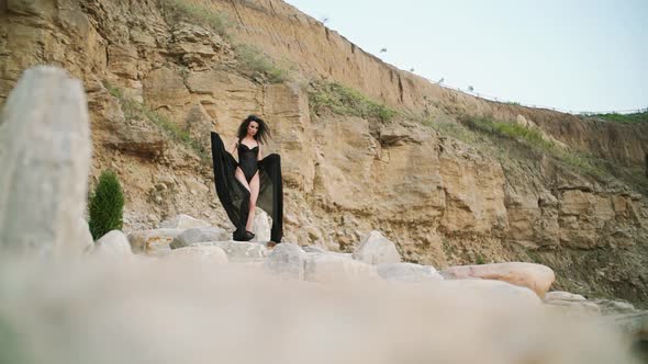 Long Hair Woman Wearing a Black Swimsuit Goesin the Evening Desert and Rock alt