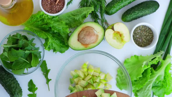 Woman Cooking Salad of Fresh Green Vegetables and Herbs alt
