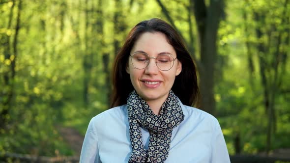 a Female Ecologist with Glasses Smiles and Looks at the Camera in the Forest alt