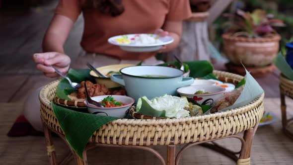 Slow motion of a woman sitting and eating Northern Thai food for dinner on wooden house balcony