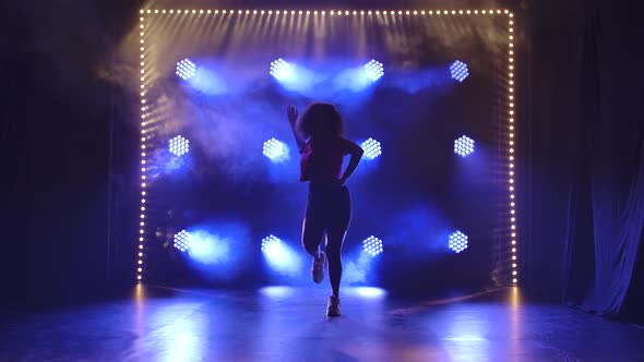 Young Girl Dancing Jazz Funk in the Studio in Slow Motion. Silhouette Against the Background of Blue alt