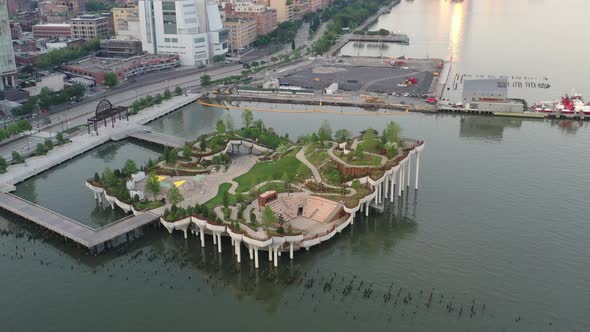 An aerial view over Manhattan's Little Island, a public green space on a sunny morning. The camera d alt
