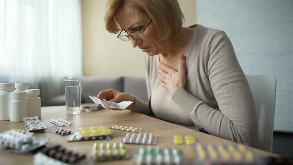 Sad Woman Looking at Table Full of Pills and Sighs, Old Age Disease, Addiction alt