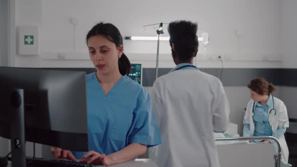 Medical Asisstant Typing Disease Symptom While Specialist Practitioner Doctors Monitoring Sick Man alt