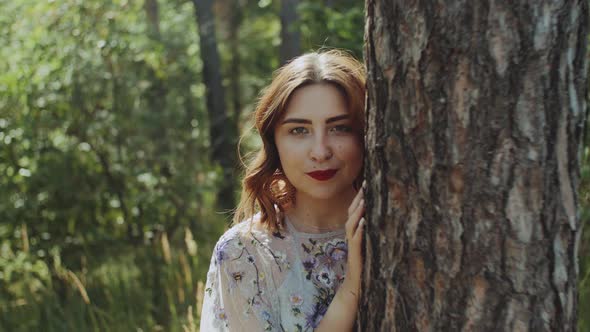 Portrait of Beautiful Young Caucasian Woman with Red Lips Posing in the Forest Near Tree Bark alt