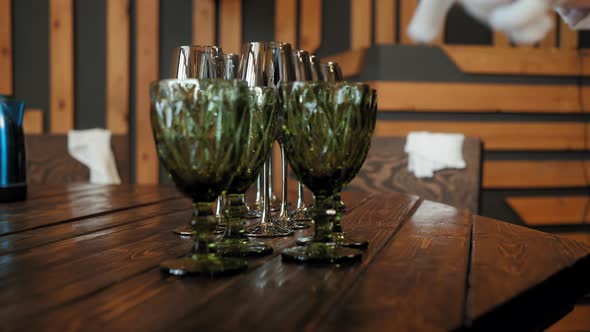 Waitress Placing Wineglasses and Goblets on Wooden Table at Restaurant