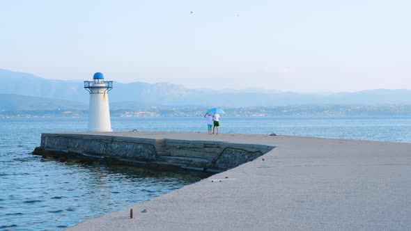 Two Boys Playing on the Pier Near Lighthouse. Young Tourists Having Fun on Quayside alt