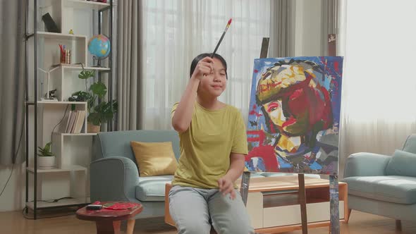 Asian Artist Girl Holding Paintbrush Wipe The Sweat Before Crossing His Arms And Smiling alt