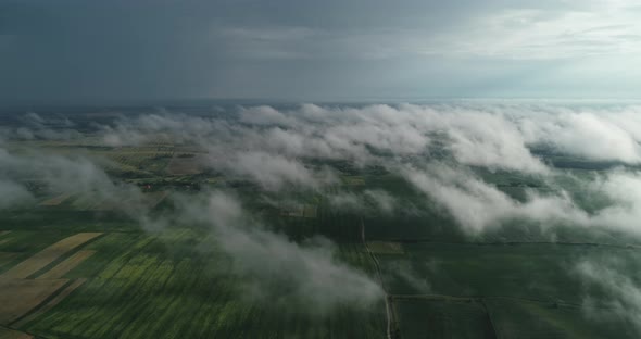 Green Fields Of Aerial View Can Be Seen Through The Clouds.  alt