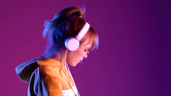 Teen Girl Wear Headphones Listen Music Dancing on Purple Neon Studio Background alt