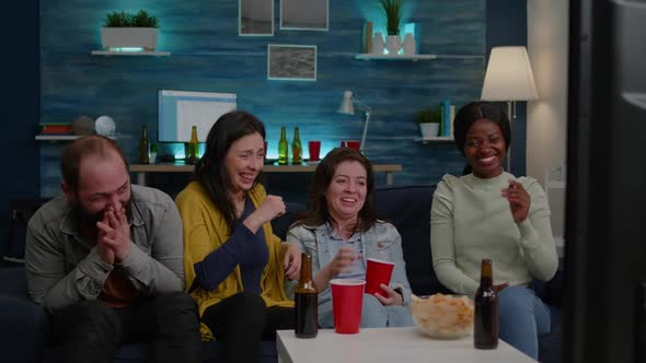 Multiracial Friends Laughing Together While Sitting on Couch alt