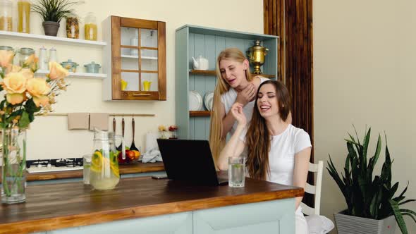 Two Joyful Young Women Making Online Video Call On Laptop, Waiving Hands And Laughing