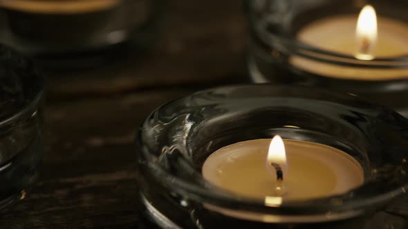 Tea candles with flaming wicks on a wooden background - CANDLES 009 alt