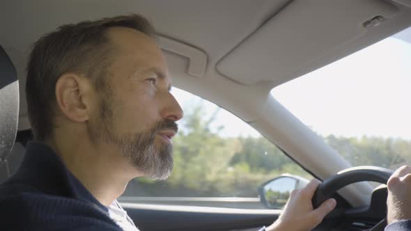 A Middleaged Handsome Caucasian Man Drives a Car on a Highway  Side Closeup