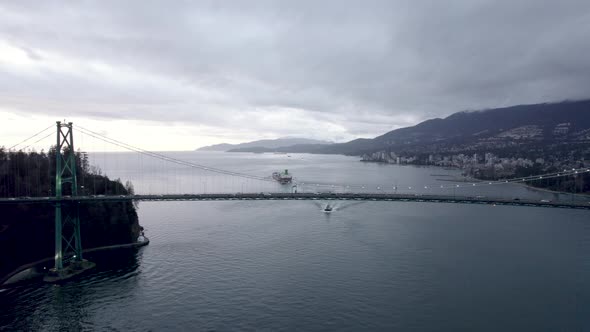 Ship sailing on Burrard Inlet fjord with Lions Gate bridge in foreground., Vancouver in Canada. Aeri alt