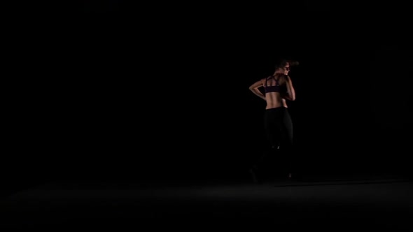 Young Girl Jumps Dancing Contemp in the Shadow on Black Background, Slow Motion alt