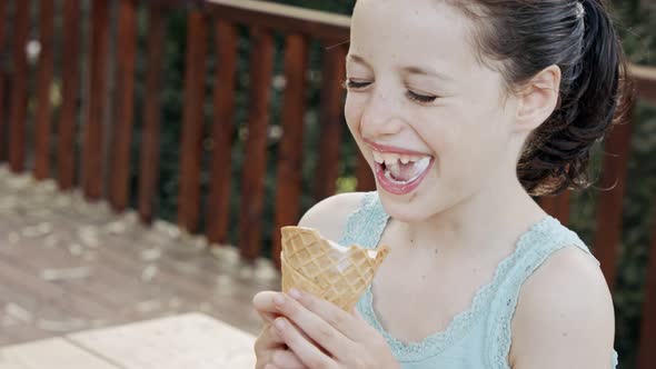 Young girl eating Ice Cream from a cone, enjoying and laughing alt