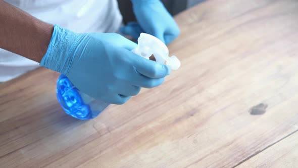 Hand in Blue Rubber Gloves Holding Spray Cleaning Flat Surface alt