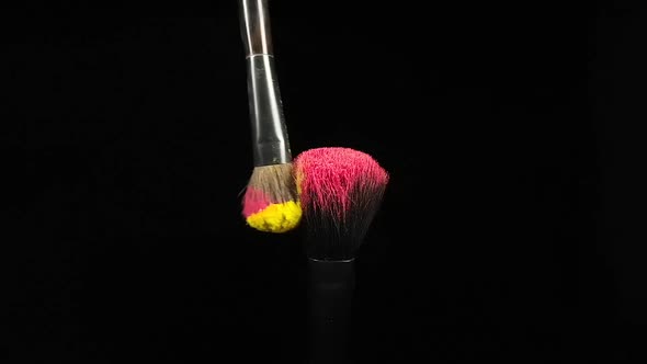 Makeup Brushes Touch Each Other on Black Dark Background and Small Particles of Color Cosmetics alt