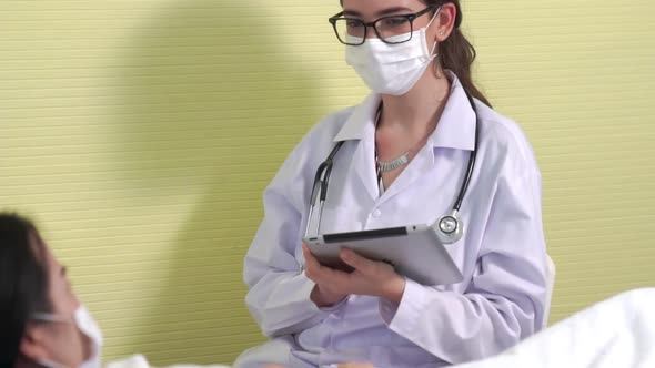 Doctor Wearing Face Mask Proficiently Talks with Patient at Hospital Ward alt