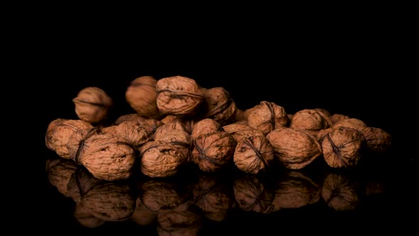 Walnuts Falling Into a Pile of More Walnuts, Black Background alt