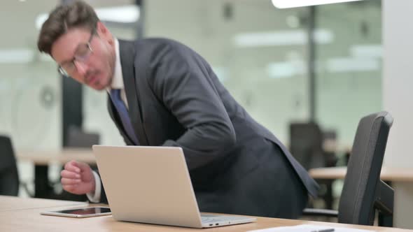Middle Aged Businessman Coming Back and Starting Work on Laptop in Office  alt