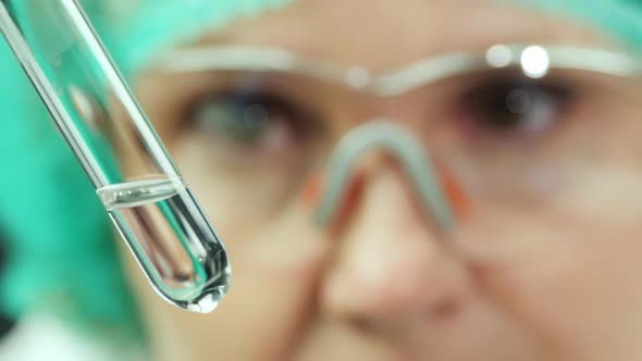 Closeup Portrait  a Female Lab Technician Looks at a Test Tube with Water alt