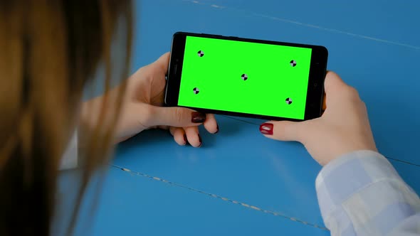 Woman Looking at Black Smartphone with Empty Green Screen - Chroma Key Concept