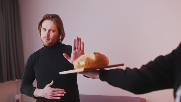 Young Caucasian Man Gluten Intolerant Refusing To Take Loaf of Bread alt